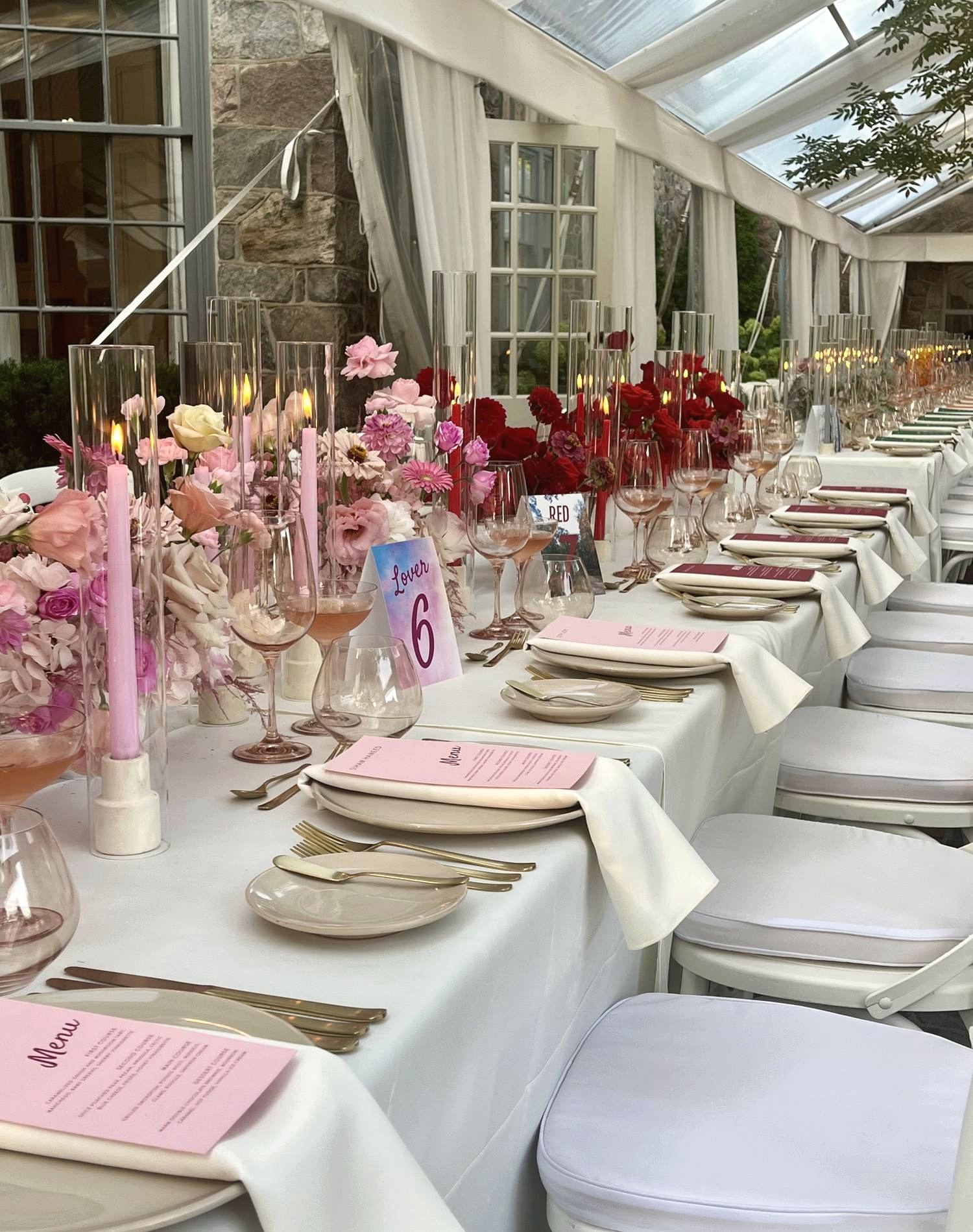 A candlelit reception table styled with pink and red florals